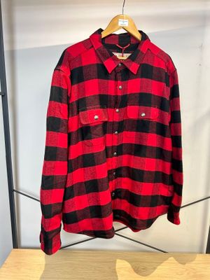 une chemise à carreaux rouges et noirs suspendue à un portant