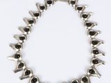 a silver necklace with black stones on a white background