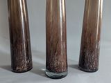 three glass vases sitting on a table with a white background