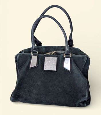 black sued handbag with silver metal accents on a white background