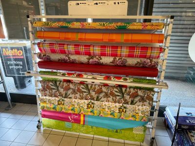un présentoir de tissus colorés sur un chariot dans un magasin
