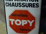 une enseigne indiquant « Réparation de chaussures » sur la façade d'un immeuble