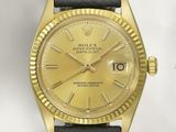 une photo d'une montre Rolex en or montée sur un bracelet en cuir noir