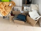 un tas de vêtements et d'autres objets rangés dans des cartons posés par terre