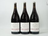 trois bouteilles de vin rouge sont alignées sur une surface blanche