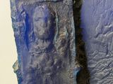 a sculpture of a man on a rock with blue paint