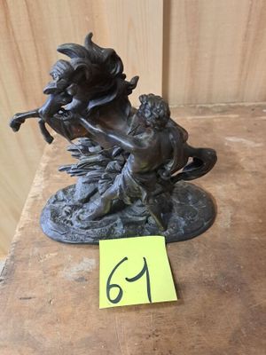 une statue en bronze représentant une femme et un chien, posée sur une table