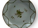 a green and white plate on a stand on a white surface