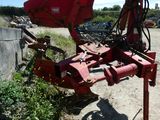 une photo d'un engin agricole rouge garé sur le bord de la route