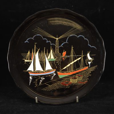 a black plate with a painting of boats on it