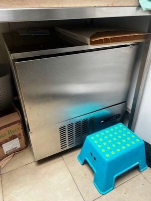 un tabouret bleu devant un réfrigérateur en acier inoxydable