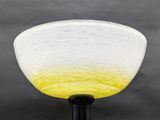 a yellow and white glass bowl on a black stand