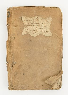 an old book with writing on it sitting on a white surface