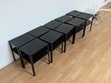 quatre tables noires dans une pièce aux murs blancs