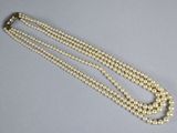 a close up of a white pearl necklace with a gold clasp