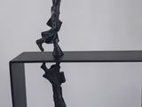 a black sculpture of a man holding a basketball ball on top of a glass table