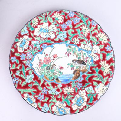 une assiette rouge décorée d'un oiseau et de fleurs