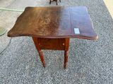 an old wooden table with a small drawer on top of it