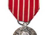 une médaille d'argent entourée d'un ruban rouge et blanc