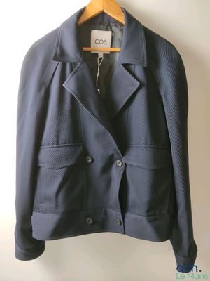 the jacket is hanging on a hanger on the wall
