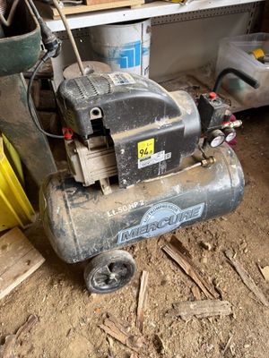 a small air compressor sitting on the ground in a garage