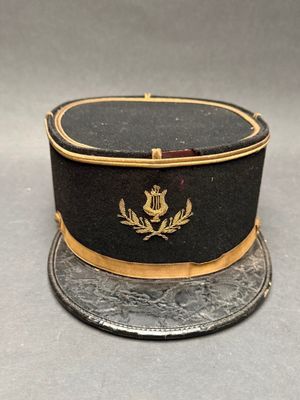 un chapeau noir orné d'une bordure dorée et d'un écusson