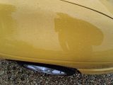 a close up of a yellow car that is parked on the street