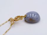 yellow gold chain with a blue stone pendant on a white background
