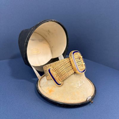 une montre ancienne présentée dans un coffret orné d'un ruban bleu et or