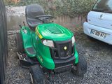 une tondeuse à gazon verte garée à côté d'une voiture blanche