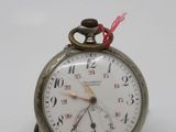 a silver pocket watch with a red string on it