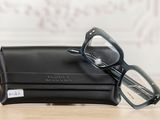 glasses in a black case on a wooden table next to a white wall