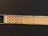 a close up of a gold watch strap on a black surface