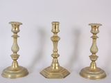 three gold candlesticks sitting next to each other on a white surface