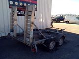 a trailer with a ladder attached to it in front of a building
