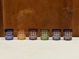 plusieurs verres de différentes couleurs sont alignés sur une surface blanche