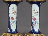 pair of blue and gold vases with flowers on them on a gray surface