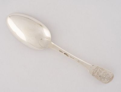 une cuillère en argent posée sur une surface blanche, avec une autre cuillère en argent au milieu