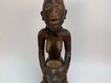 an old wooden statue of a man holding a bowl