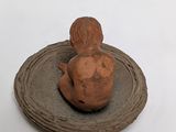 a small figurine of a baby sitting on top of a plate
