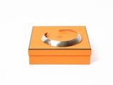 une boîte orange sur laquelle est posé un bracelet argenté