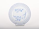 a blue and white plate on a stand on a white surface