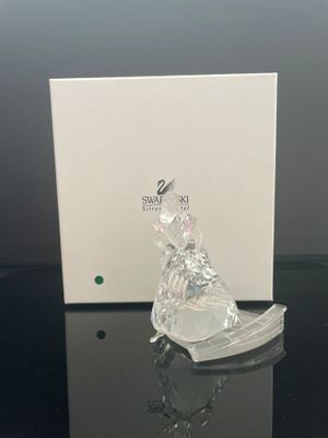 La figurine en verre est posée sur la table, à côté de la boîte.