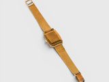 the gold apple watch is sitting on a white surface