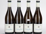 quatre bouteilles de vin sont alignées sur une surface blanche