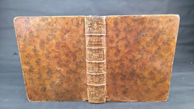 an old book with a brown cover sitting on top of a table