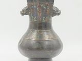 a metal vase that is sitting on a white surface