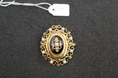 a close up of a black and gold broochle with pearls