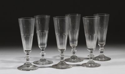 quatre verres à vin vides sont alignés sur une surface blanche