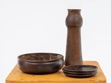 un vase marron et un bol posés sur une table en bois